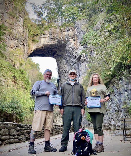 RJ and Debra in front of Natural Bridge with a park ranger posing with their certificates